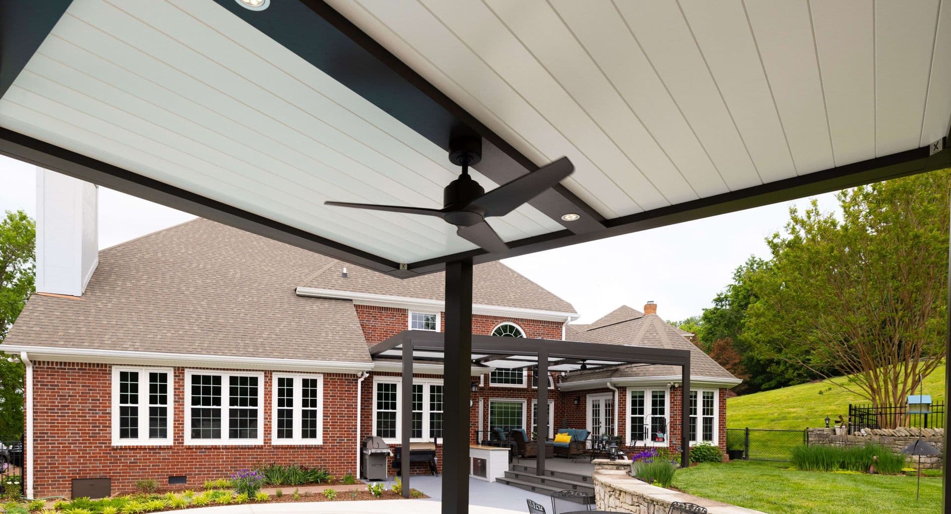 A photo of a black Struxure pergola with white Pan 6 fixed ceiling panels.