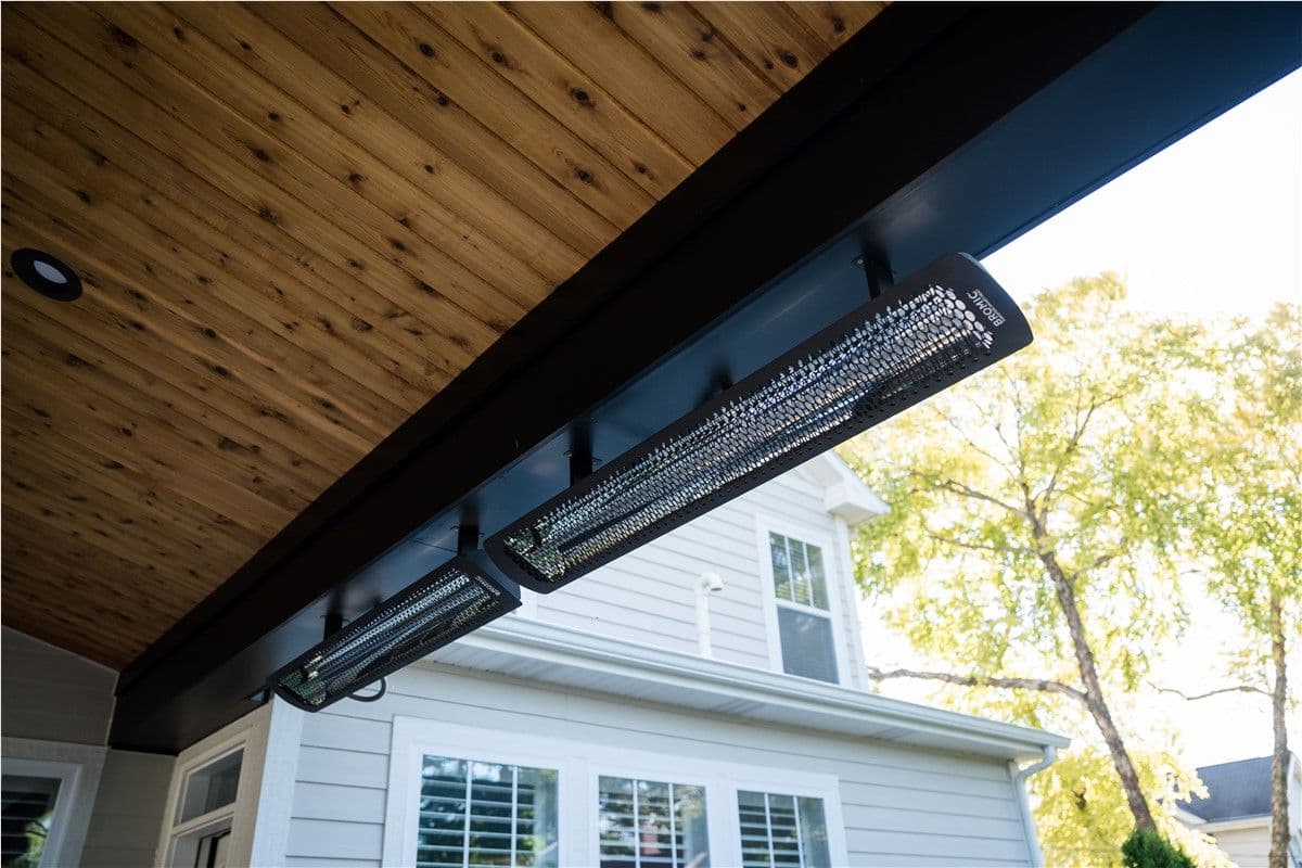 Heating lamps hang from a pergola with a wood roof.